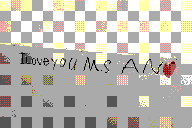 A student's writing on a whiteboard that reads "I love you Ms. An"